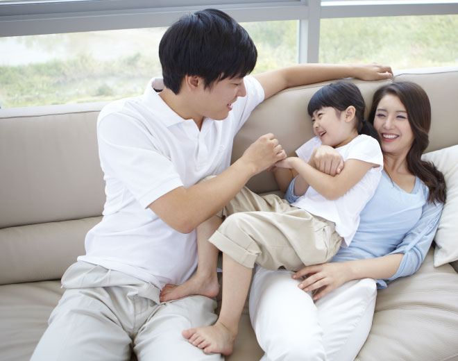 Japanese couple with young child on couch with smile